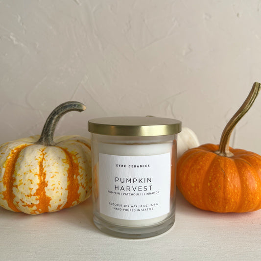 Candle labeled 'Pumpkin Harvest' with two small pumpkins on a neutral background