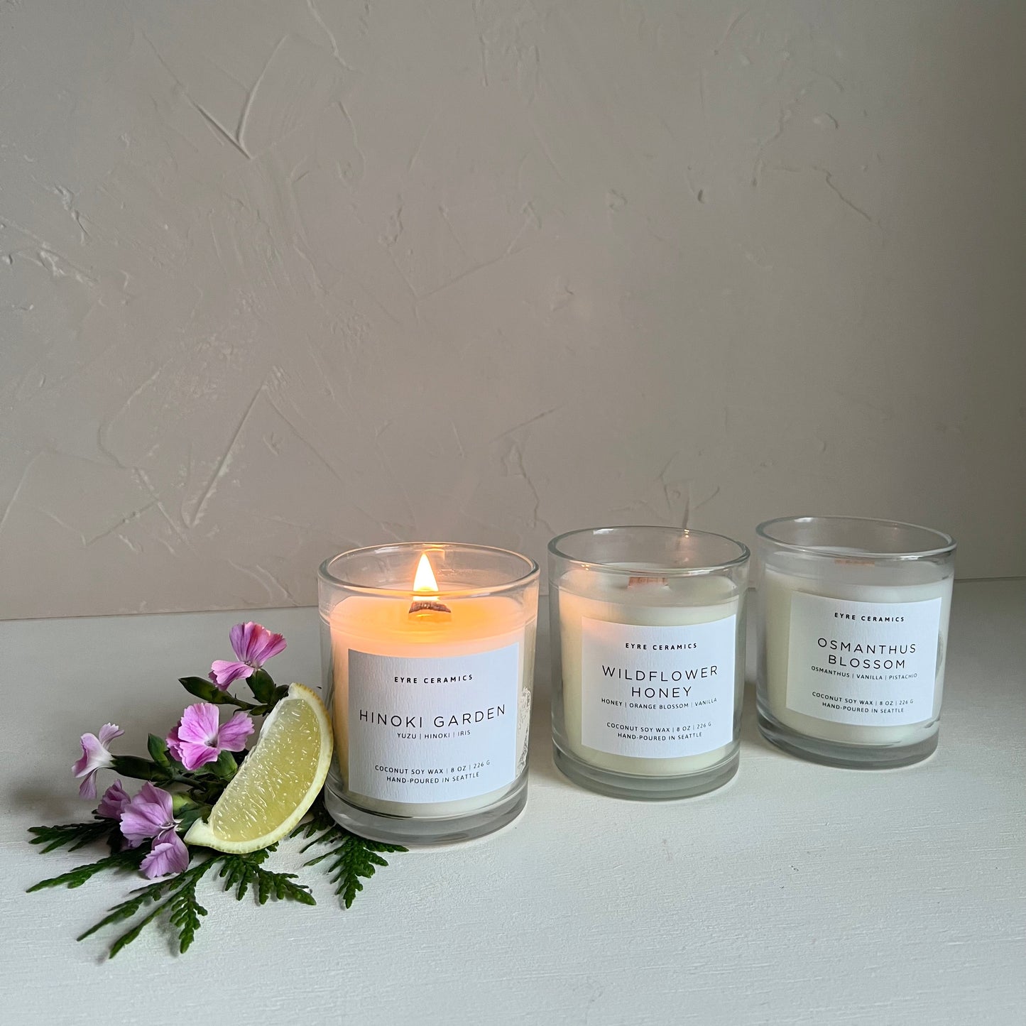 Three candles with labels on a white surface with a light gray background
