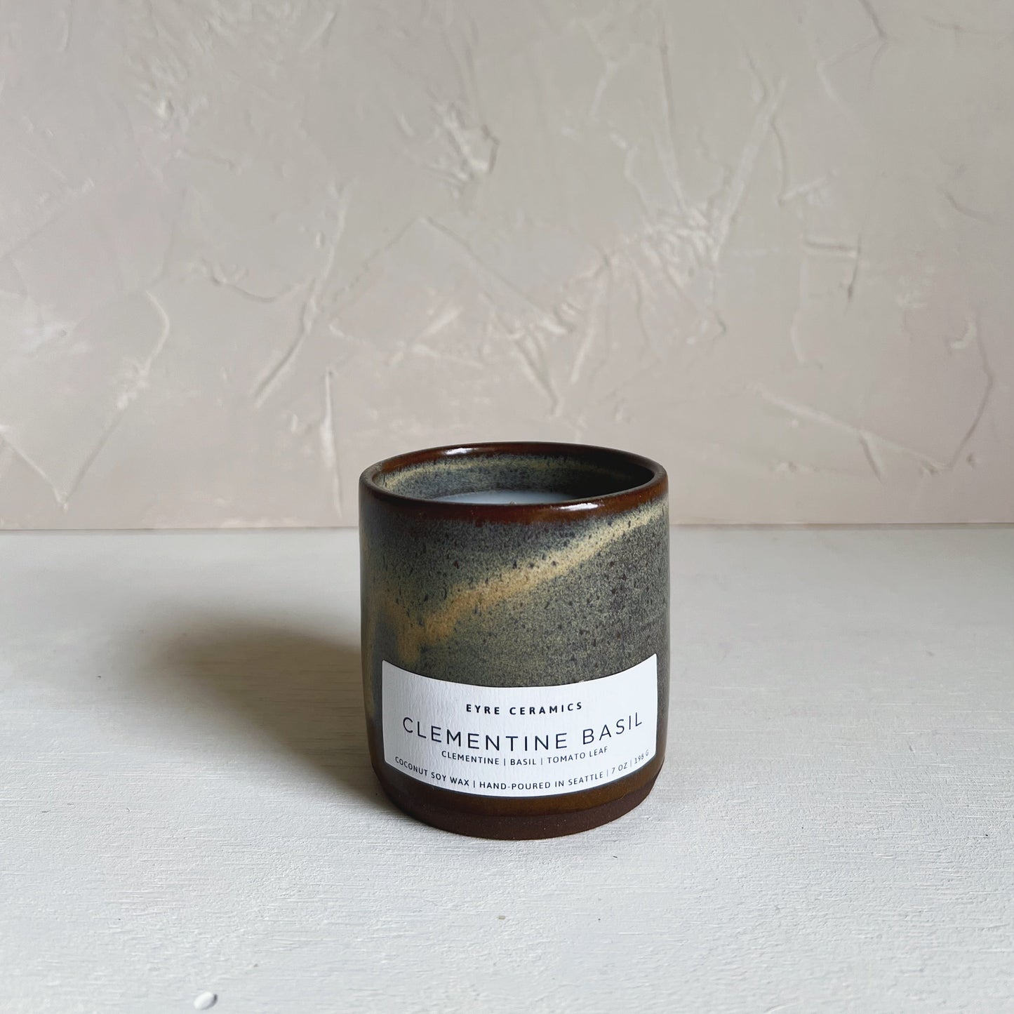 Ceramic candle with a label on a white surface and light gray background