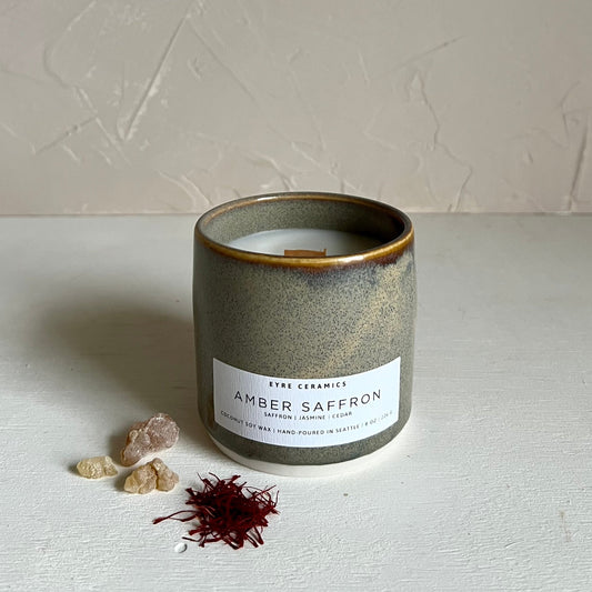 Ceramic candle with 'Amber Saffron' label on a textured surface