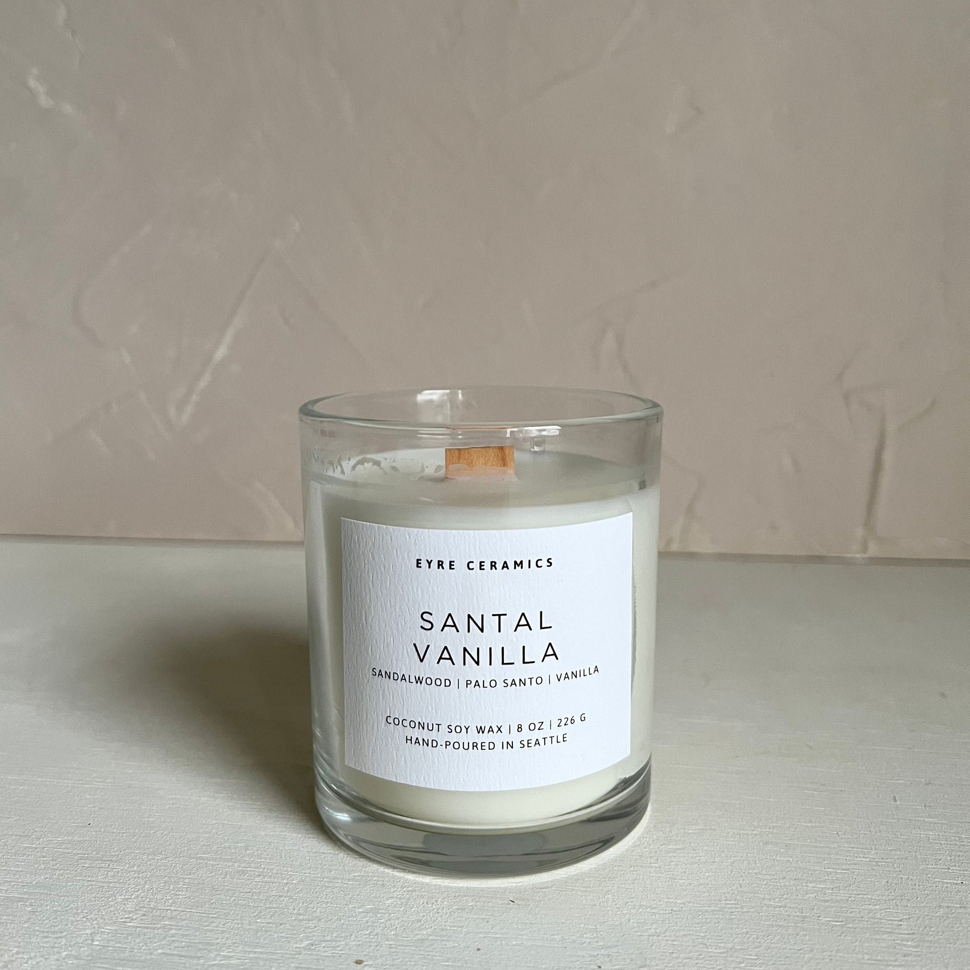 Santal Vanilla candle in a glass jar with a white label on a light gray background