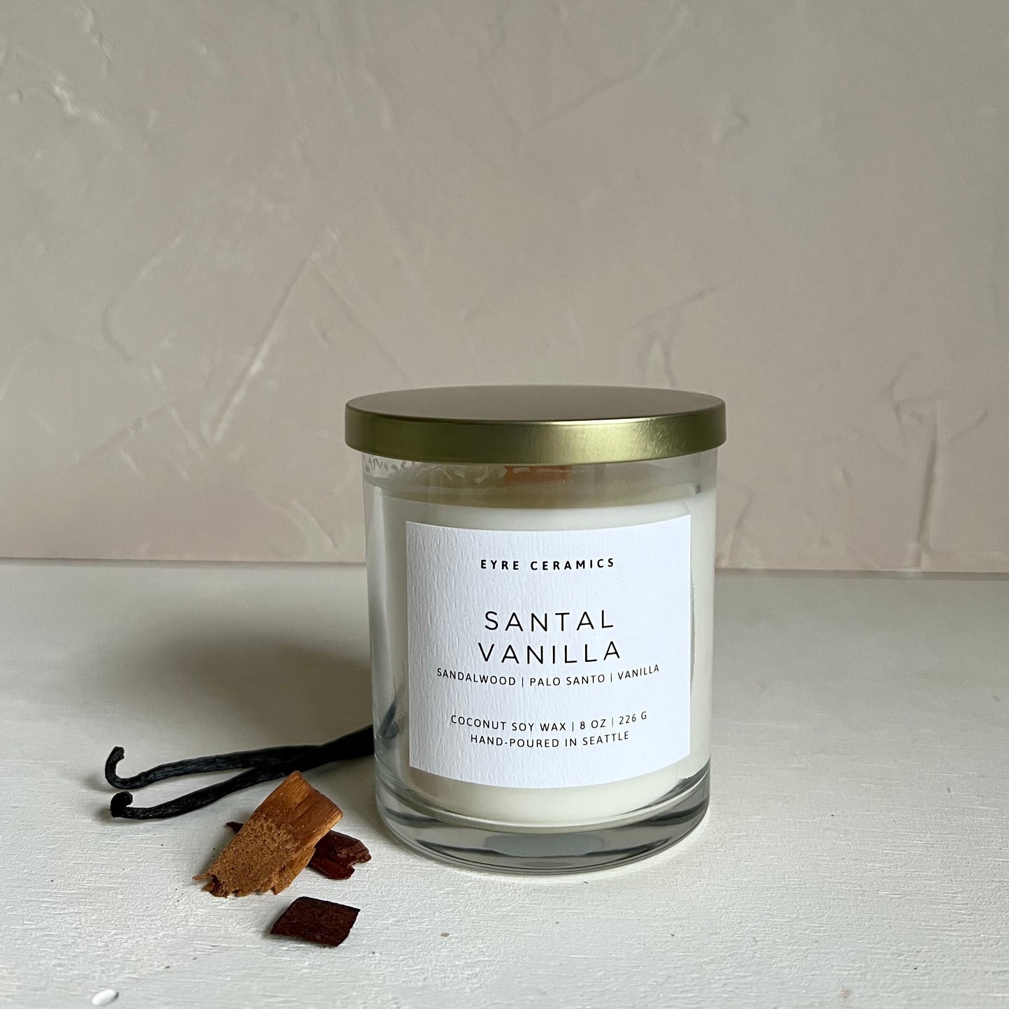 Santal Vanilla candle with vanilla beans on a light background