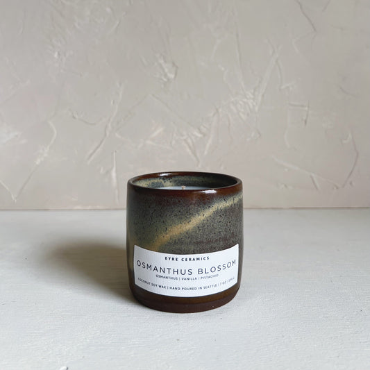 Ceramic candle with a label on a white surface and light gray background