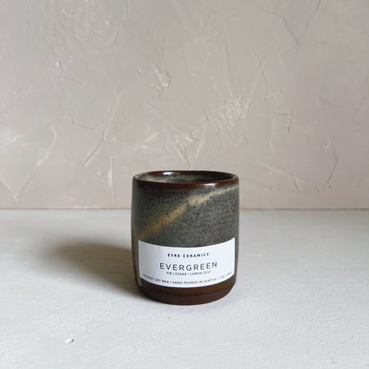 Ceramic candle with 'Evergreen' label on a white surface and light gray background