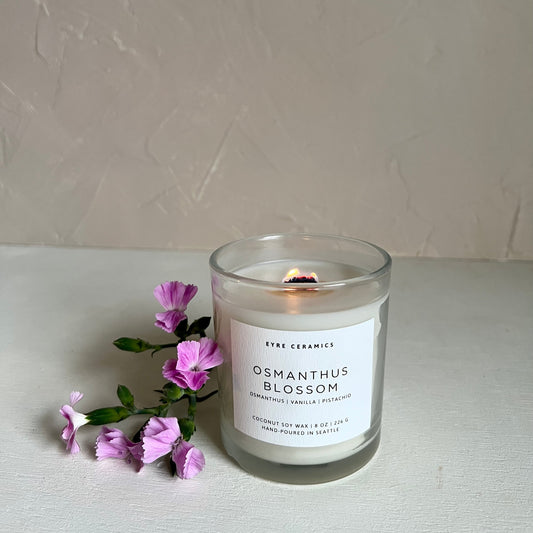 Candle labeled 'Osmanthus Blossom' with purple flowers on a light background