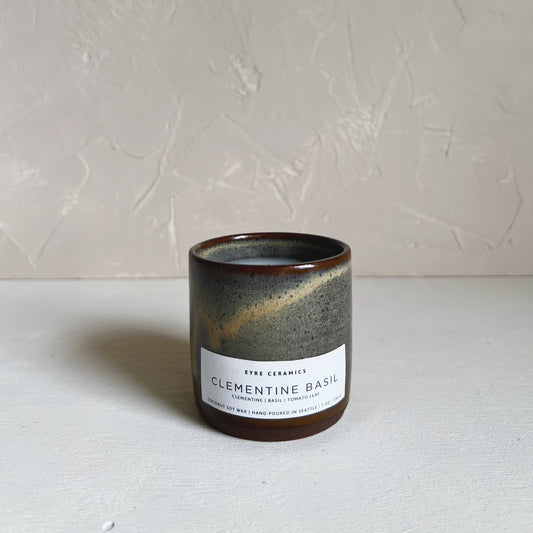 Ceramic candle with a label on a white surface and light gray background