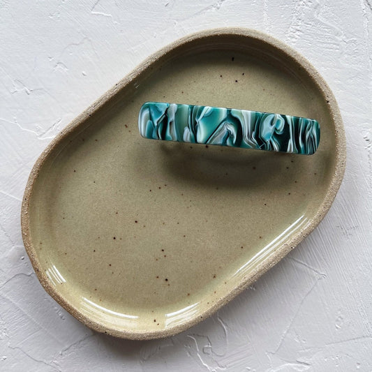 Handmade ceramic trays in various colors including Celadon, Rose, Shino, and Sky Blue, displayed on a surface.